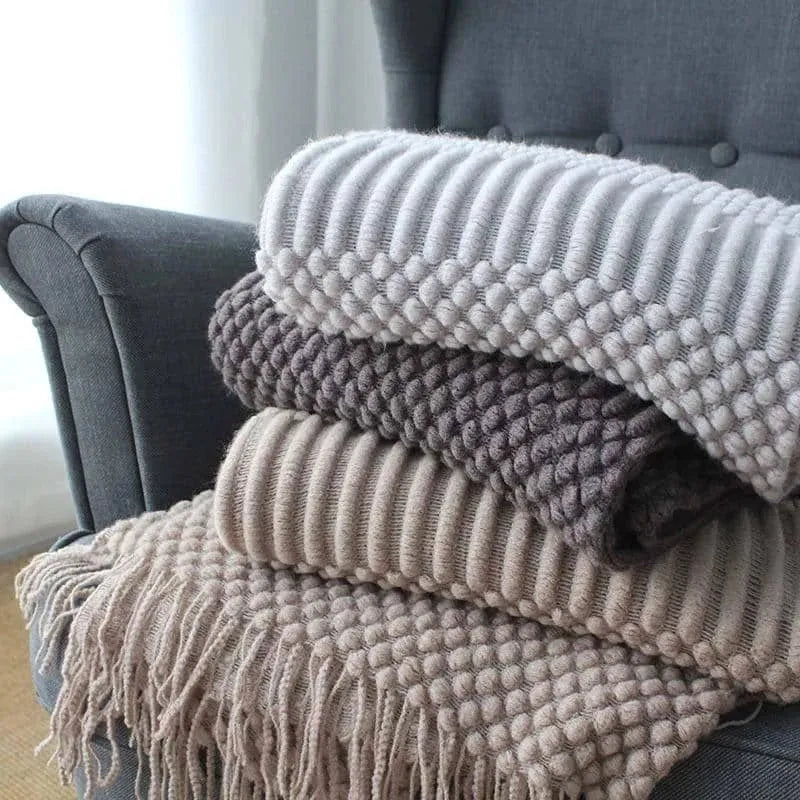 Small polyester fibre throw blanket in dark grey, folded on a sofa