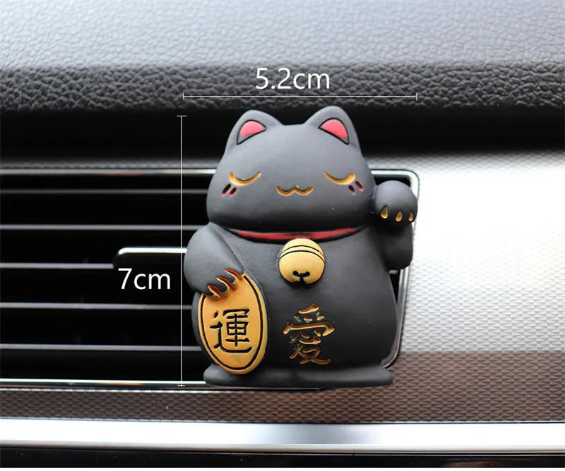 Black and white resin fortune cat ornament designed to clip onto a car air vent as an aromatherapy diffuser.