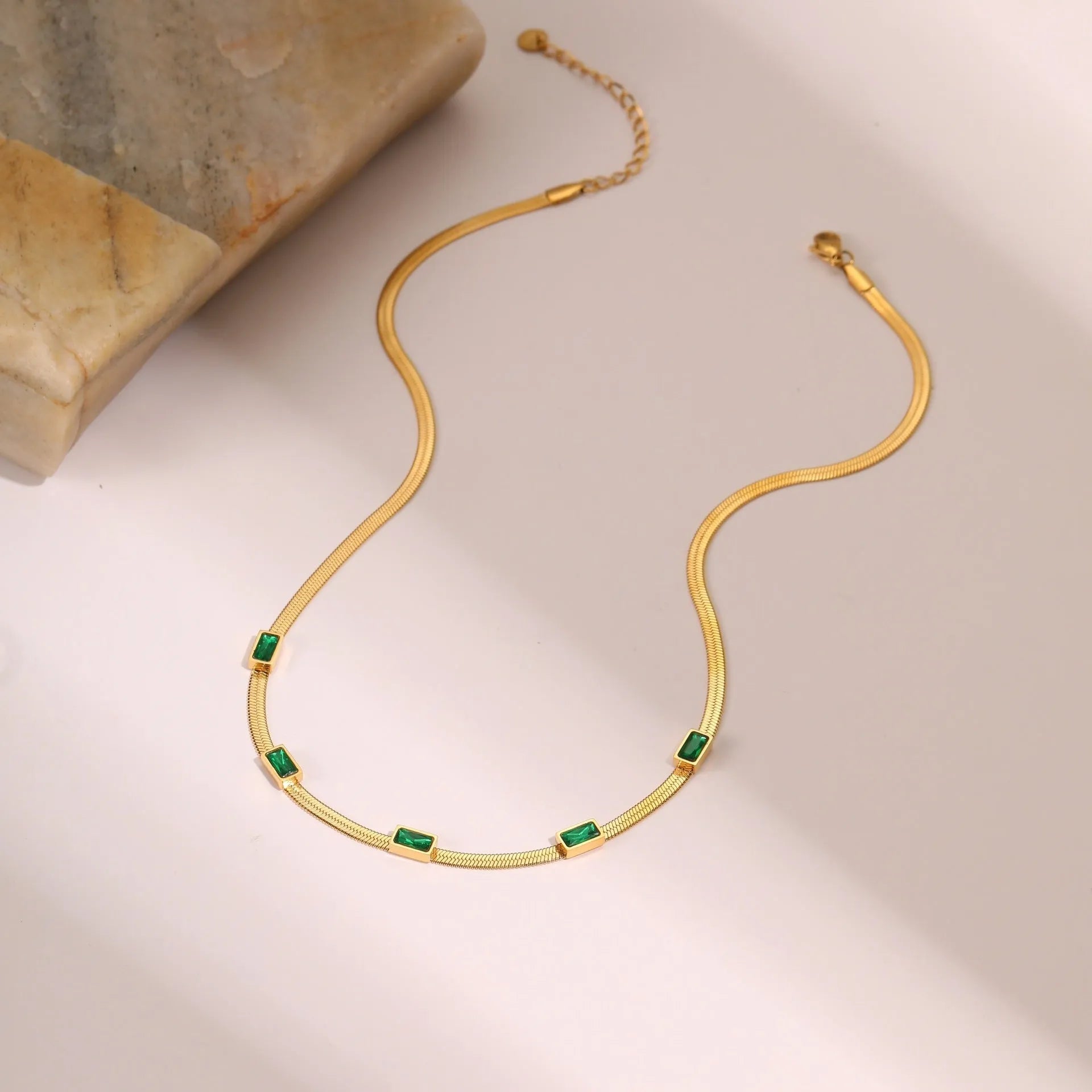 Geometric square zircon pendant on a stainless steel flat snake chain necklace with gold plating.