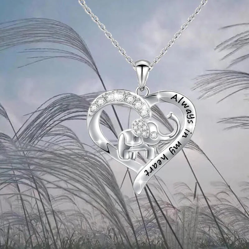 Silver alloy elephant pendant necklace with personalised letter charm on a flat surface