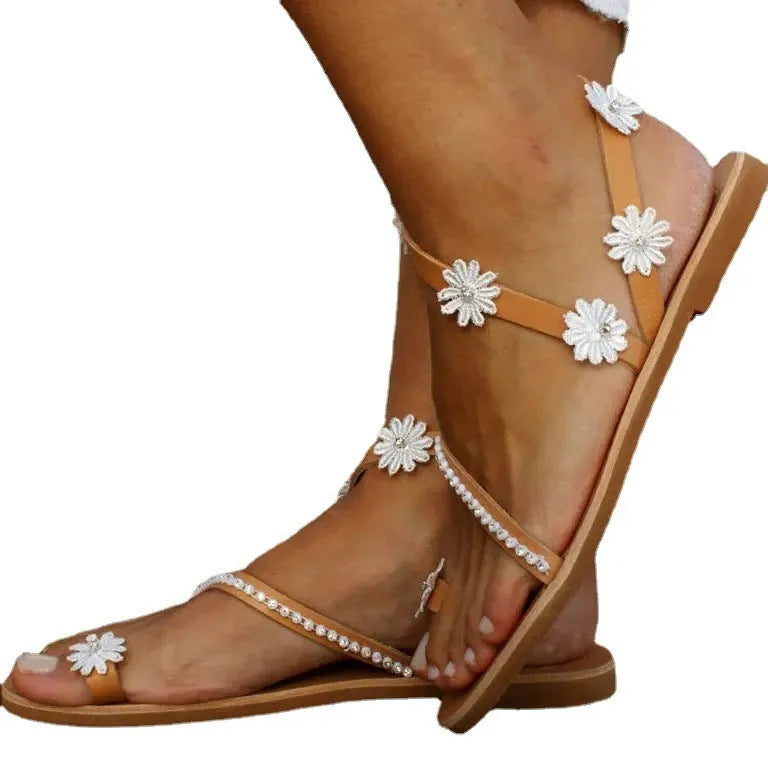 Brown women's Roman sandals with herringbone toe design and flower elements on flat rubber sole