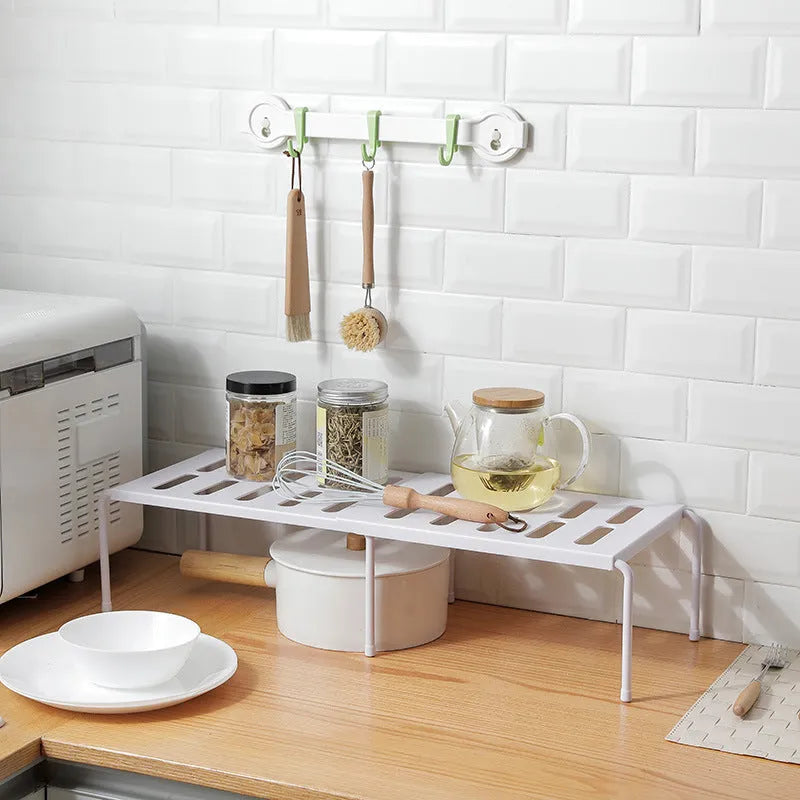 White telescopic plastic kitchen rack extended to 69cm height on kitchen countertop
