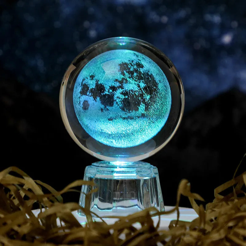 6cm transparent crystal ball ornament with illuminated inner carving of celestial designs on a table