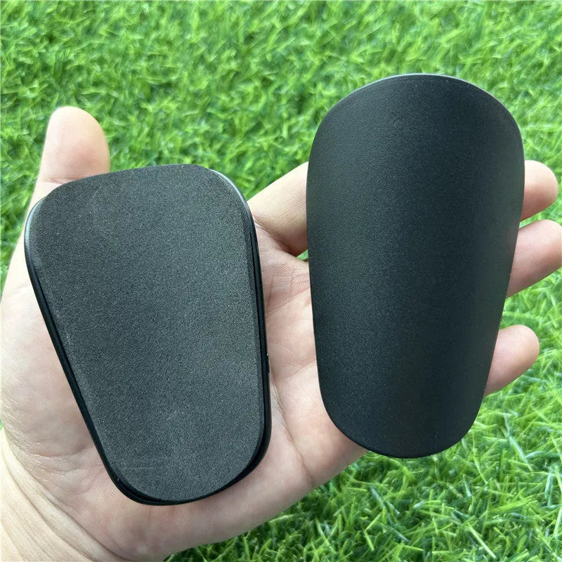 Extra small mini football shin guards in black and white measuring 8cm by 5cm