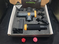 Black fascia massage gun with four different coloured massage heads on a table