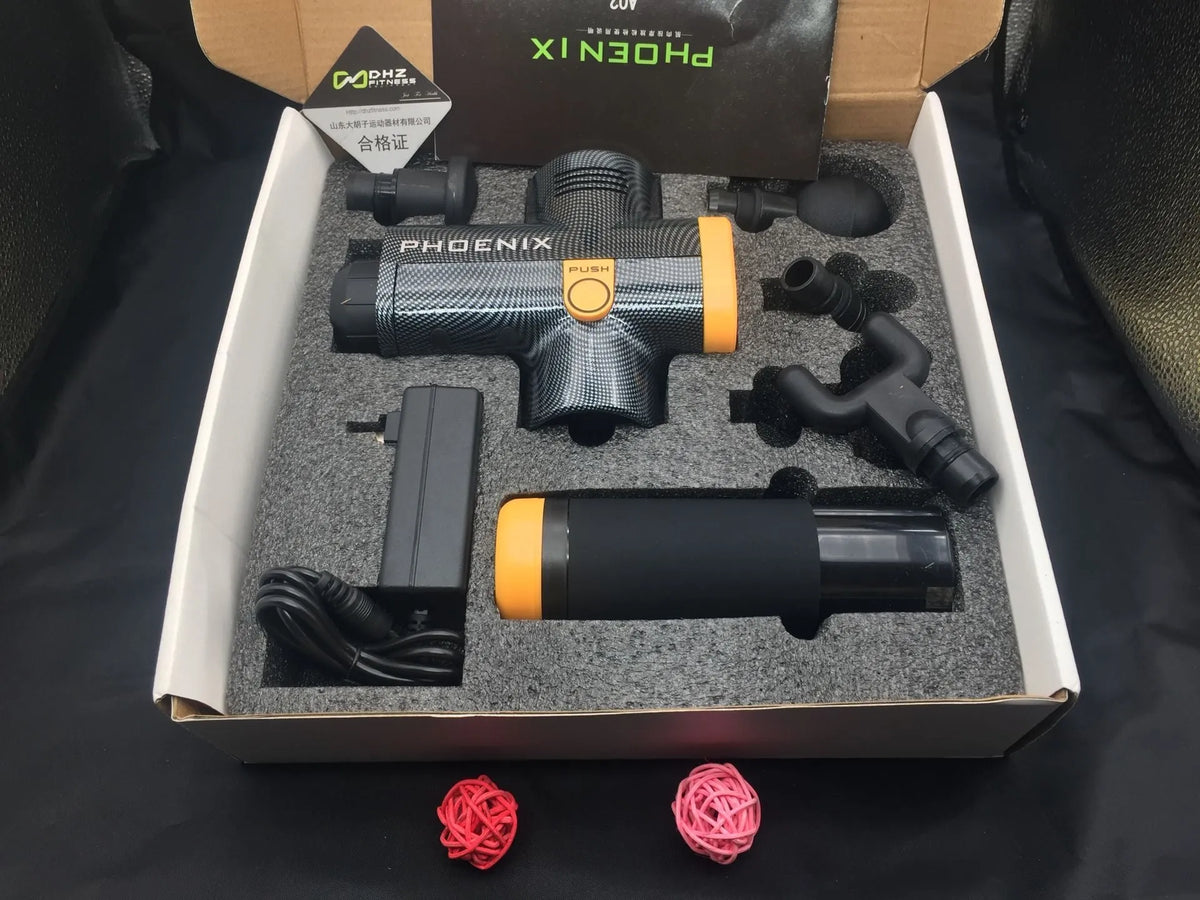 Black fascia massage gun with four different coloured massage heads on a table