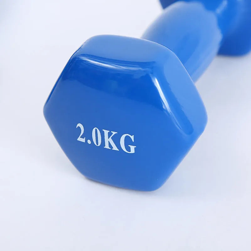 Bright green and pink plastic fitness dumbbells with glossy finish on a wooden floor.