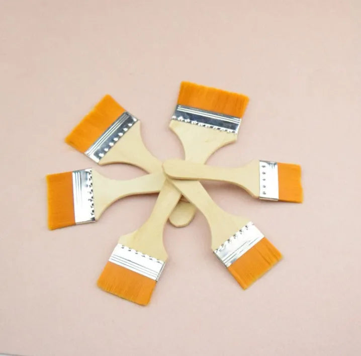 Twelve nylon board brushes with wooden handles in sizes 1 to 12 laid out on a surface