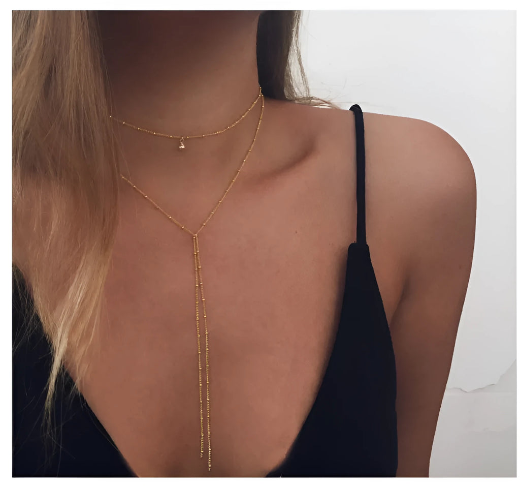 Multilayer lariat necklace in gold plated alloy on neutral background with visible 35cm and 45cm chain segments.