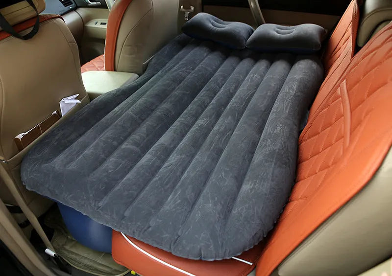 Inflatable car bed with flocked surface folded beside storage bag and two pillows