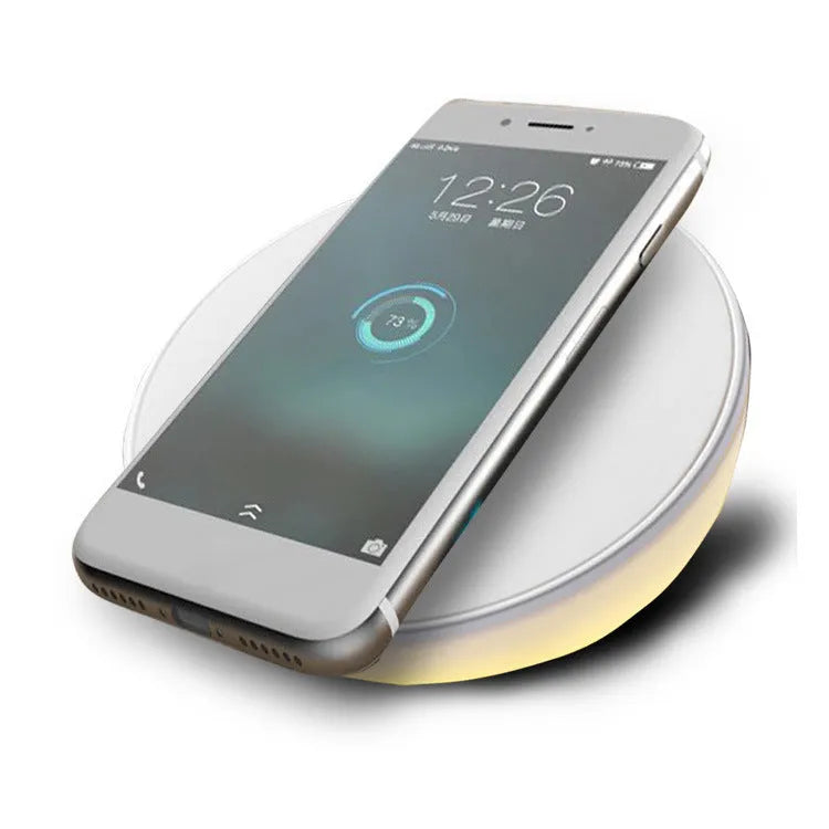 White wireless charging pad with LED digital clock display and control buttons on a desk.