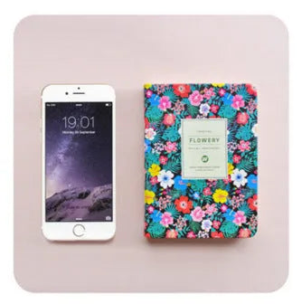 Green floral notepad with wireless binding lying open on a table, showing the Daolin paper interior.