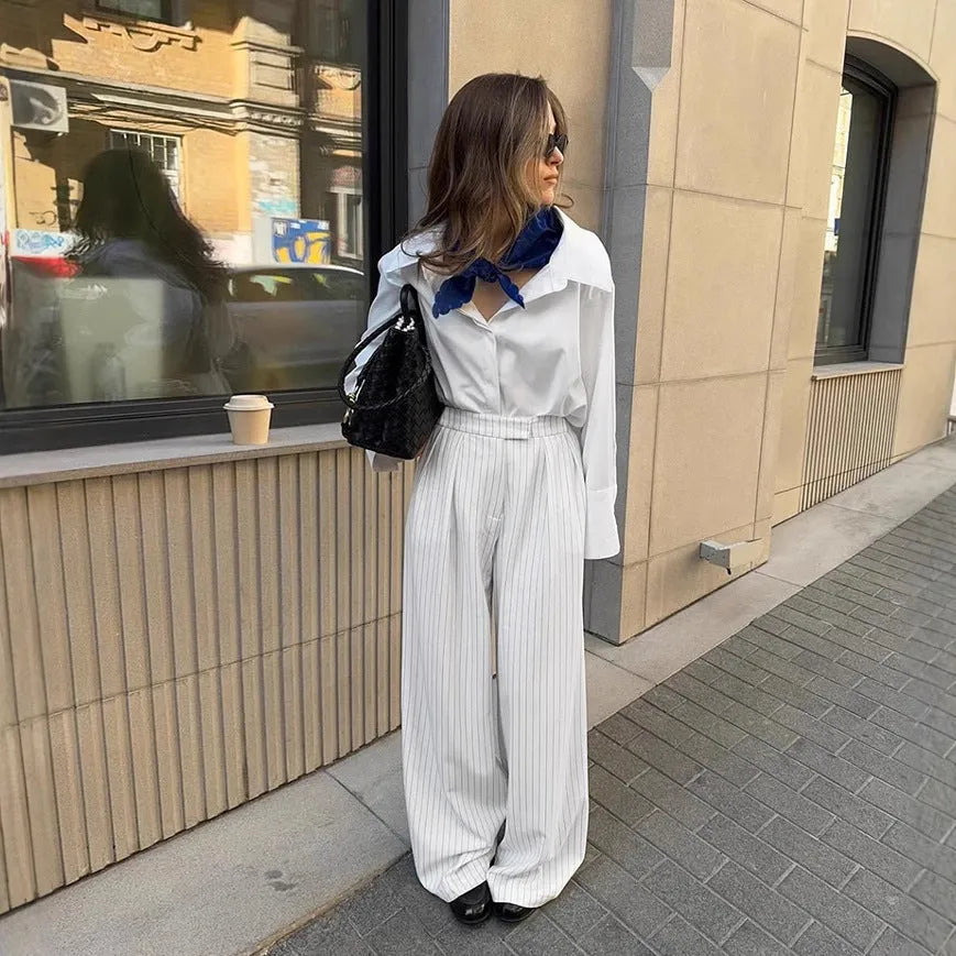 White striped wide-leg women's trousers with a loose fit and zipper fastening on a hanger.
