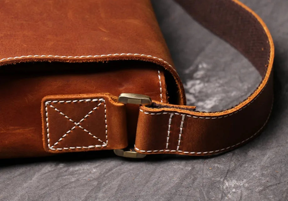 Vintage brown men's leather messenger bag showing interior compartments and adjustable shoulder strap