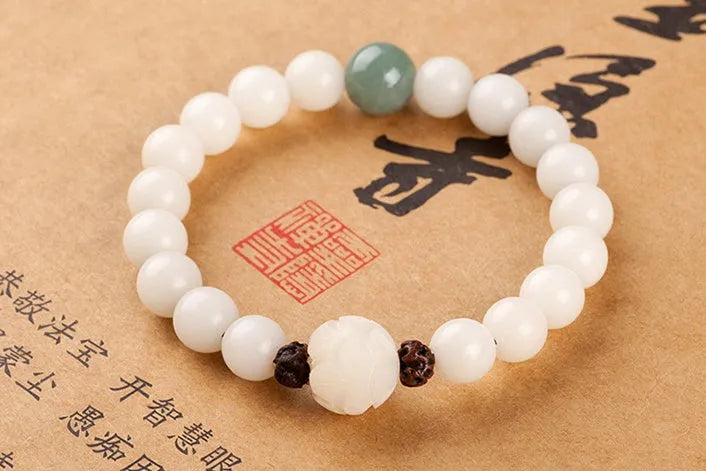 Natural white jade Bodhi bracelet with transfer beads on a neutral background