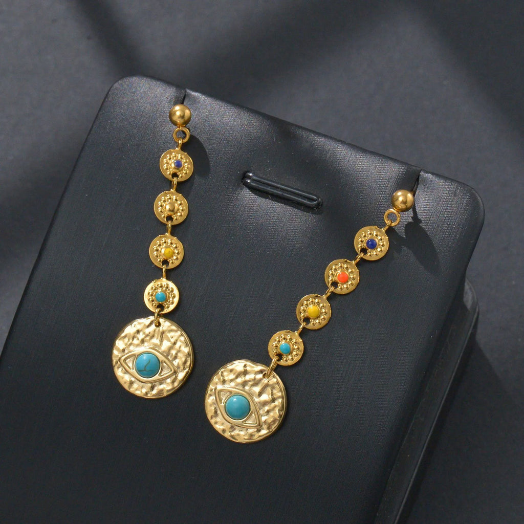 Geometric stainless steel drop earrings showing Eight Awn Star, Eye, and Shell Sun designs on a white background.