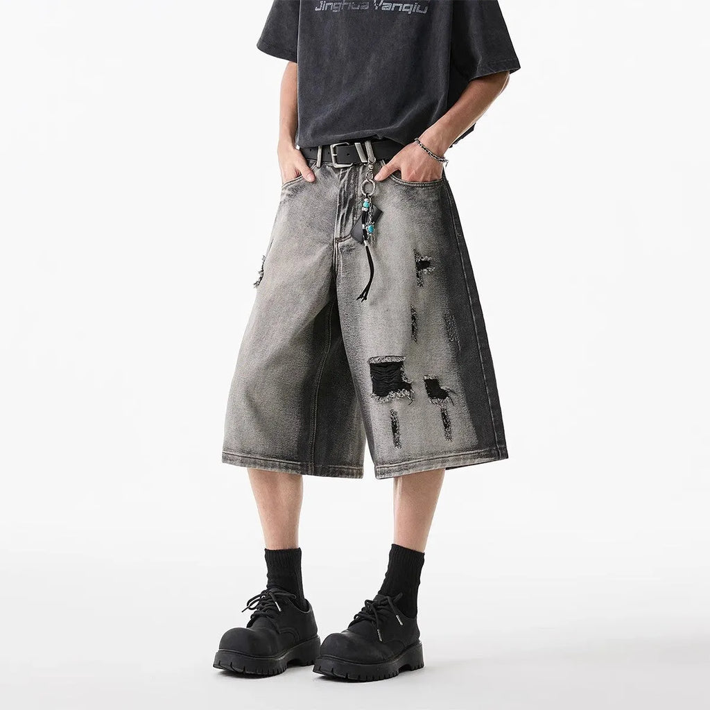 Grey distressed denim shorts with a loose cropped fit and hole details on a mannequin.
