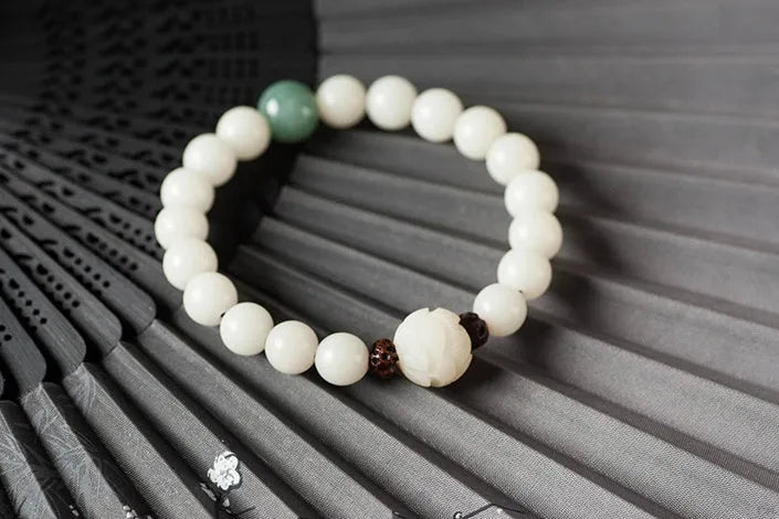 Natural white jade Bodhi bracelet with transfer beads on a neutral background