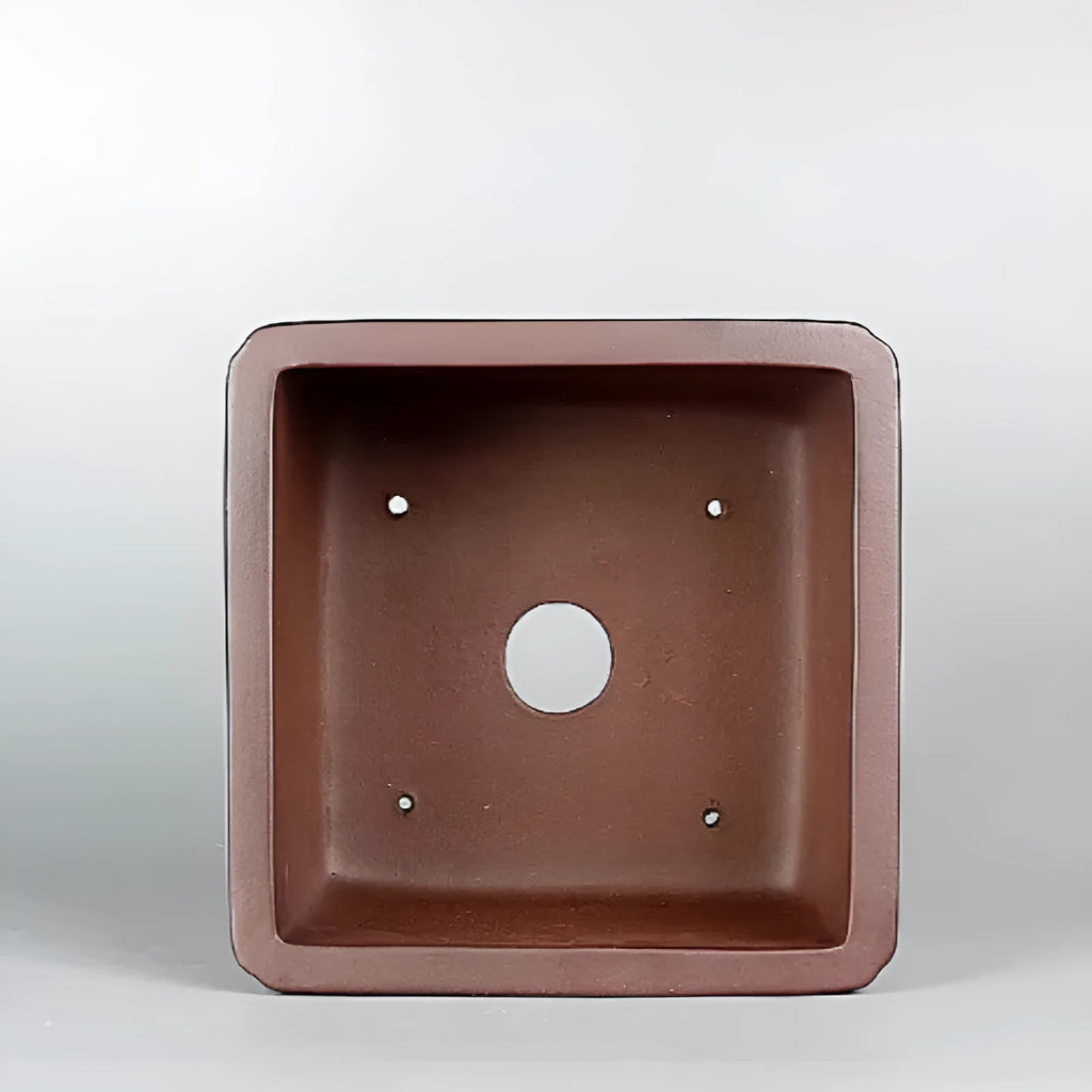 Handmade brown antique flower pot made from purple clay, shown on a surface.
