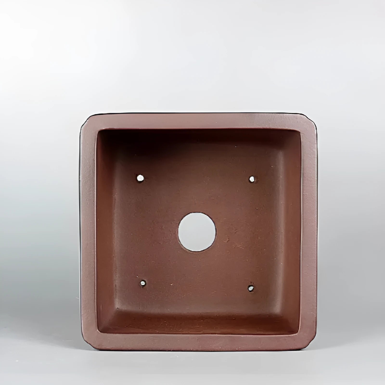 Handmade brown antique flower pot made from purple clay, shown on a surface.