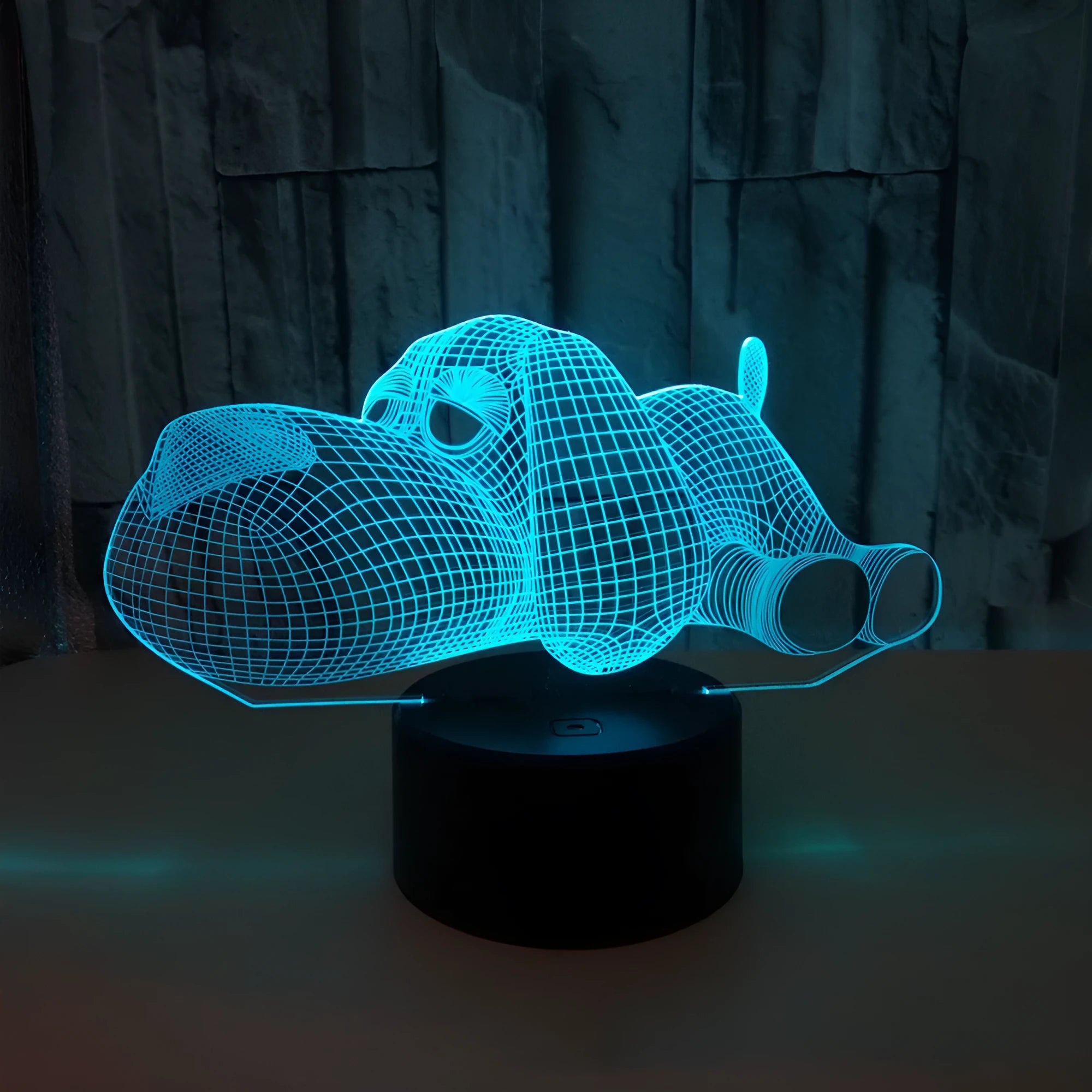 Doggo desktop lamp with 3D illusion design glowing in multiple colours on a desk.