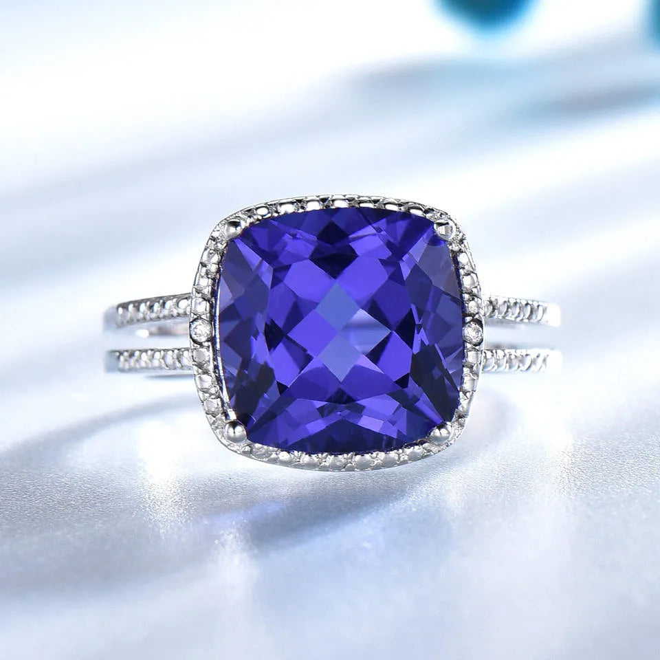 Women's sterling silver ring with a blue tanzanite gemstone on a model's hand.