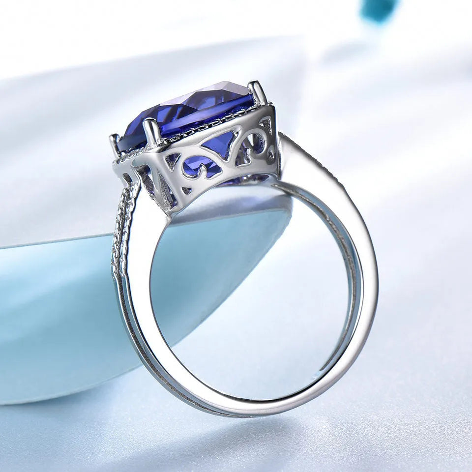 Women's sterling silver ring with a blue tanzanite gemstone on a model's hand.