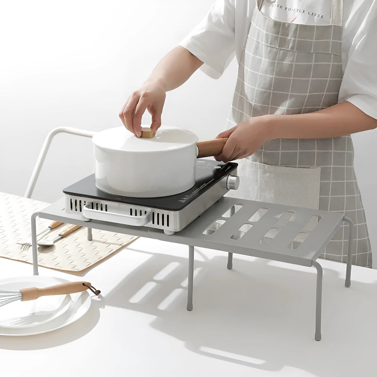 White telescopic plastic kitchen rack extended to 69cm height on kitchen countertop