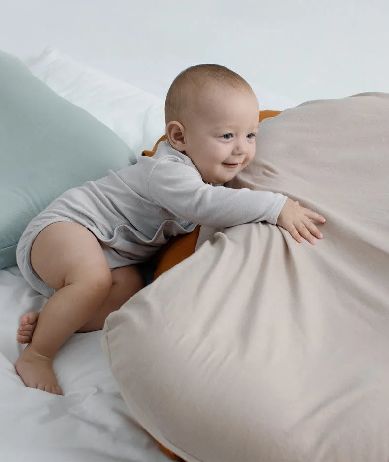 Beige portable baby nest crib cot for newborns on a neutral background.