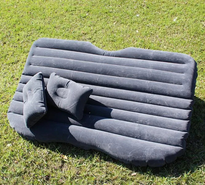 Inflatable car bed with flocked surface folded beside storage bag and two pillows