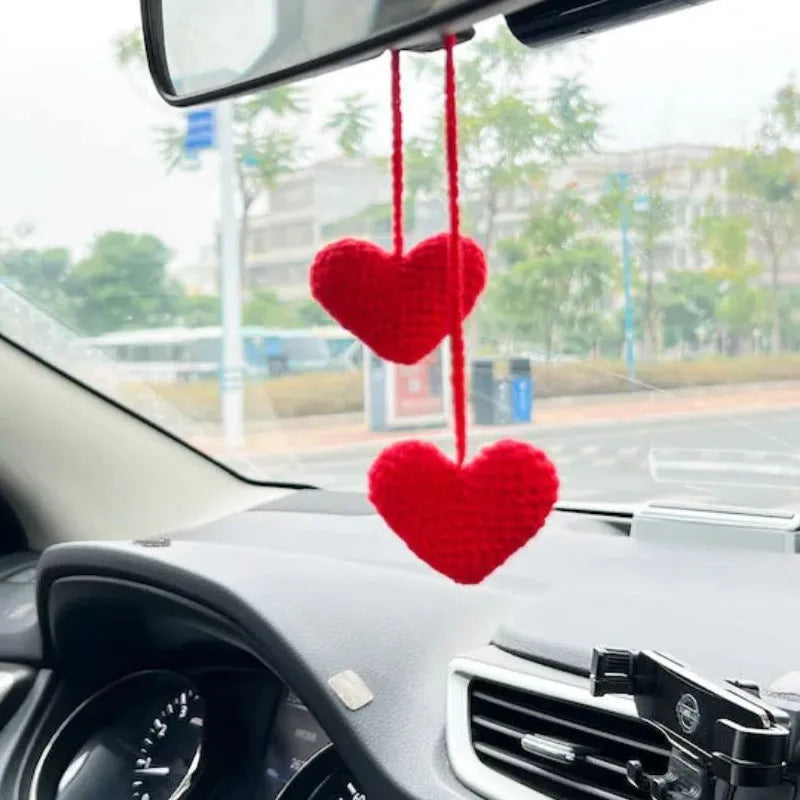 Green and white crocheted car plant decoration with hanging rope on a car dashboard.
