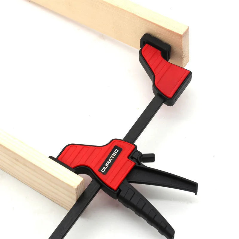 Black plastic woodworking clamp with rubber grip showing quick adjustment key and clamping mechanism
