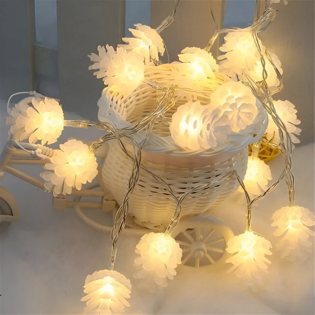 Warm white LED pine cone string lights draped over a surface, showing plastic shell details and battery pack.