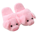 Pink pig-shaped plush floor slippers on a clean floor, showing the short plush fabric and pig design details.