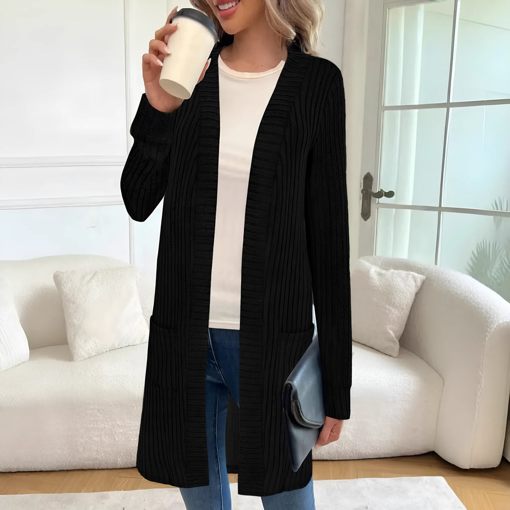 Woman wearing a loose grey long sleeve knitted cardigan jacket with pockets.