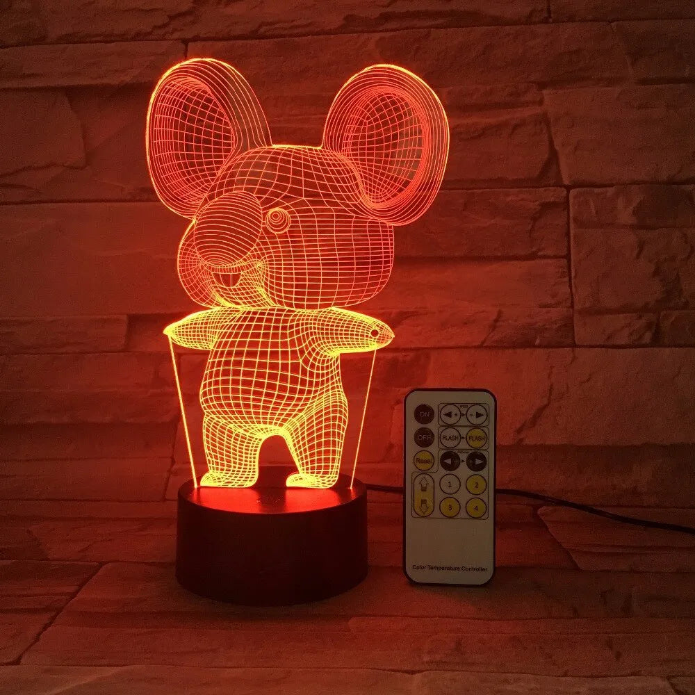 Black koala night light with colourful LED glow on a small table, showing remote control.