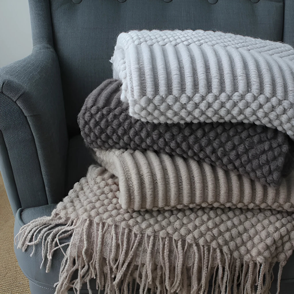 Small polyester fibre throw blanket in dark grey, folded on a sofa