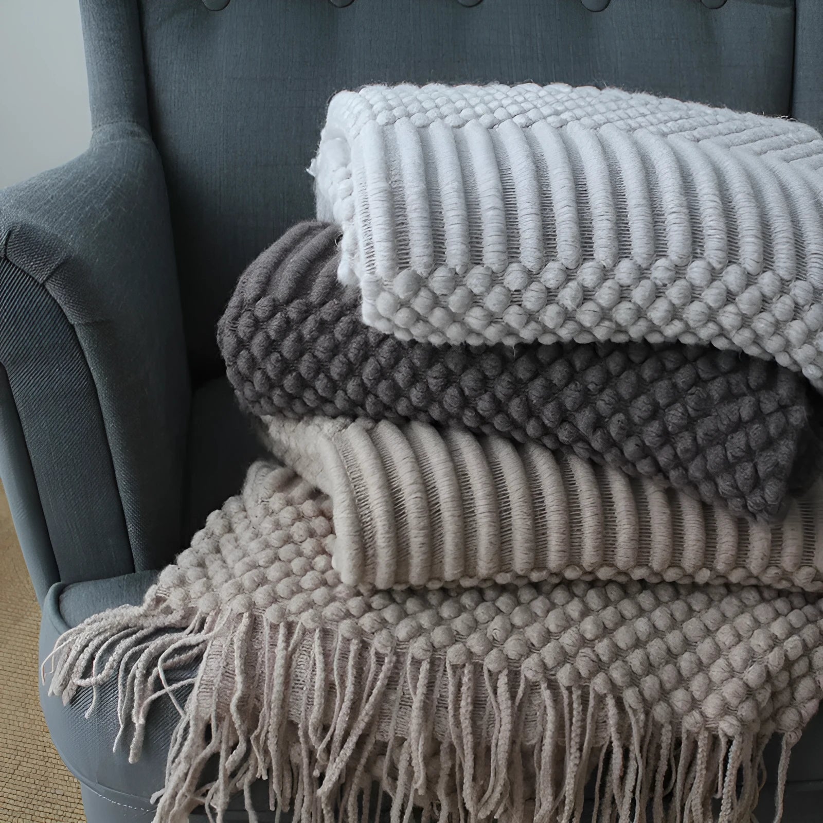 Small polyester fibre throw blanket in dark grey, folded on a sofa