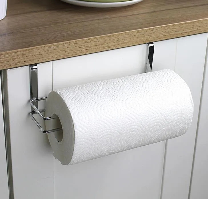 Silver stainless steel paper towel rack hanging on a kitchen cabinet door