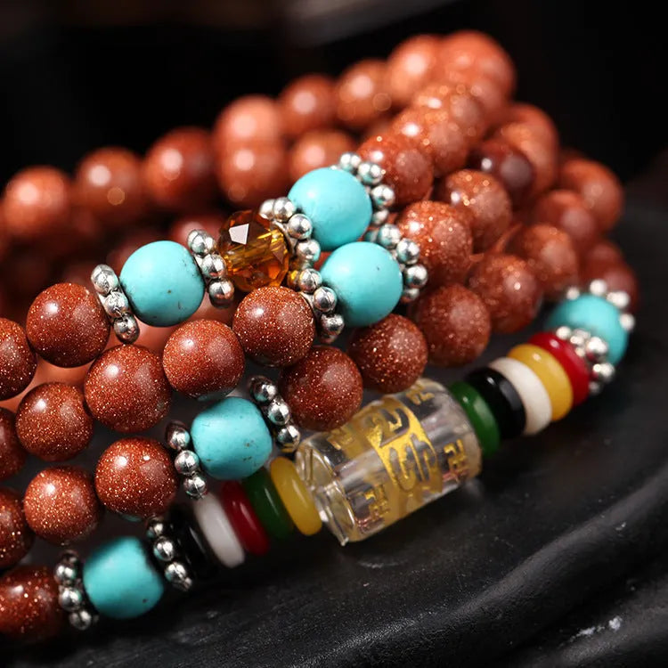 Golden star stone nugget bracelet with mantra beads and a retro fu charm on a wrist.