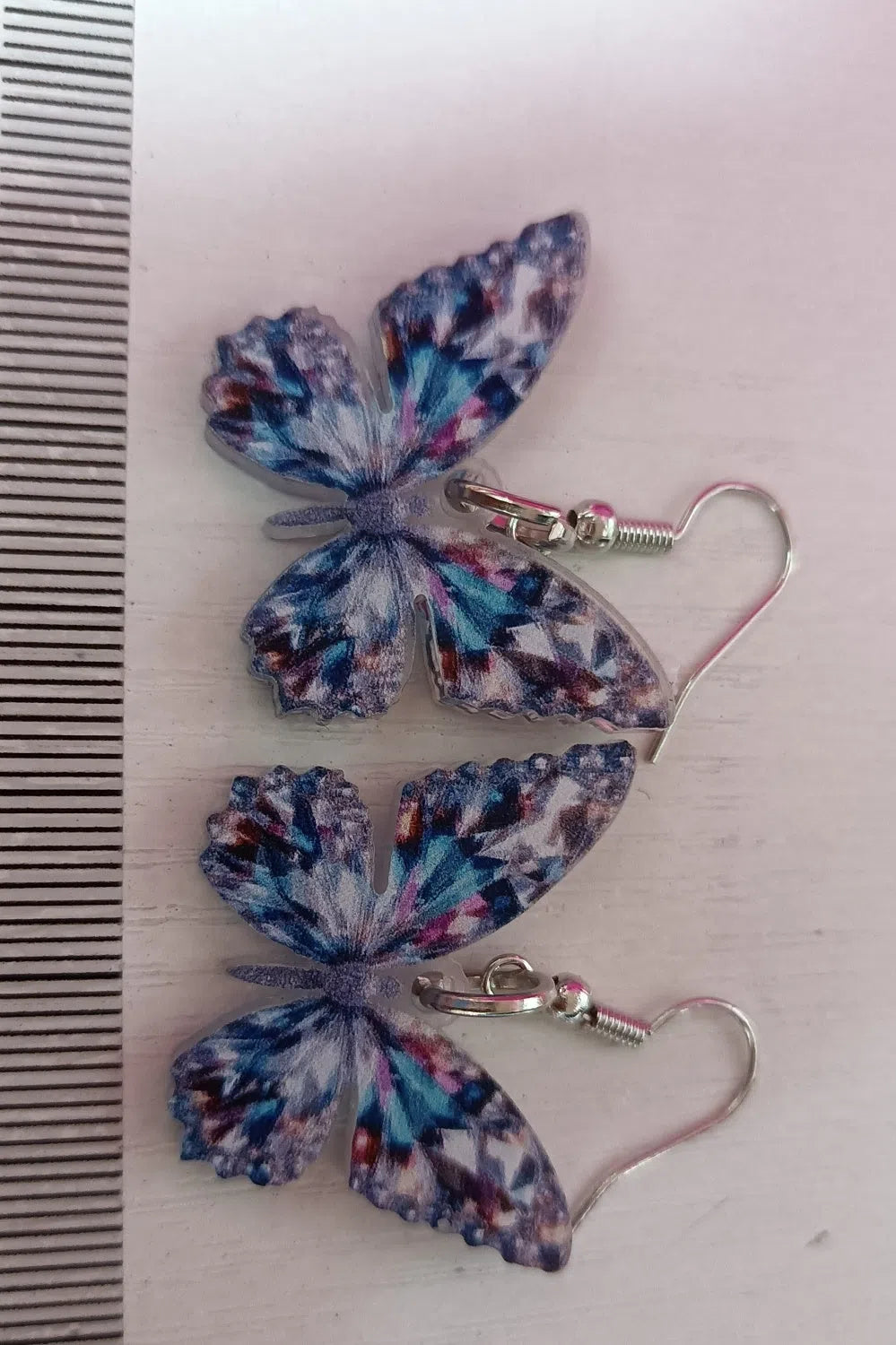 Colourful printed 2D acrylic earrings with butterfly design on a light background