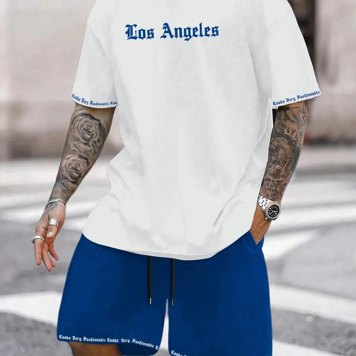 Man wearing a blue printed short-sleeve top and matching shorts from a two-piece sports casual set.