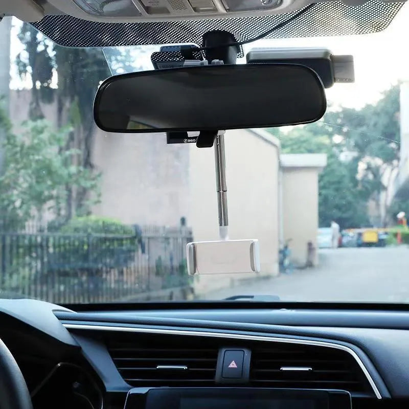 Black ABS plastic mobile phone bracket mounted on car rearview mirror holding smartphone