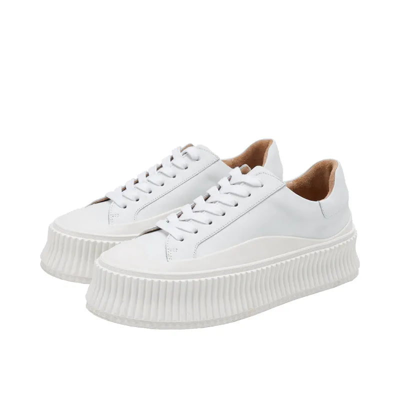 Women's white chunky platform trainers with a thick rubber sole, suede upper, and cross-binding detail.
