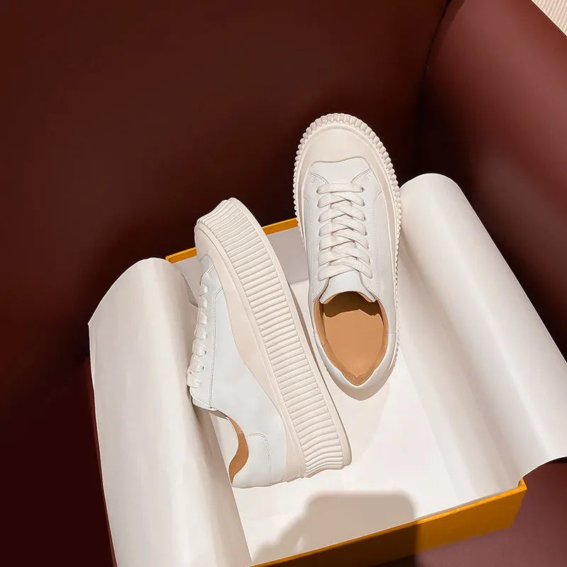 Women's white chunky platform trainers with a thick rubber sole, suede upper, and cross-binding detail.