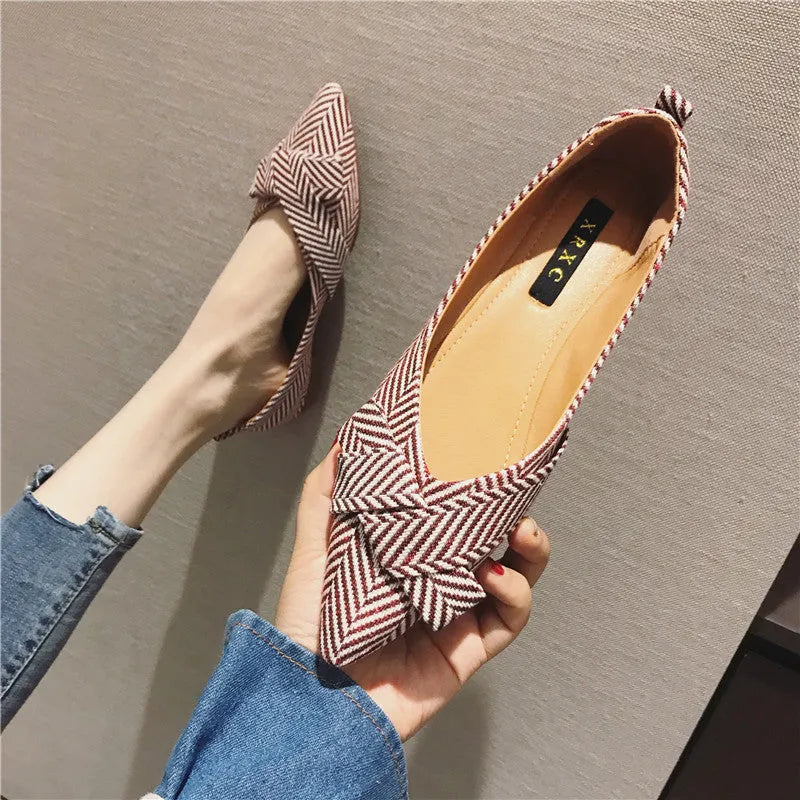 Women's red pointed toe shallow mouth flats with a low flat heel on a white background.