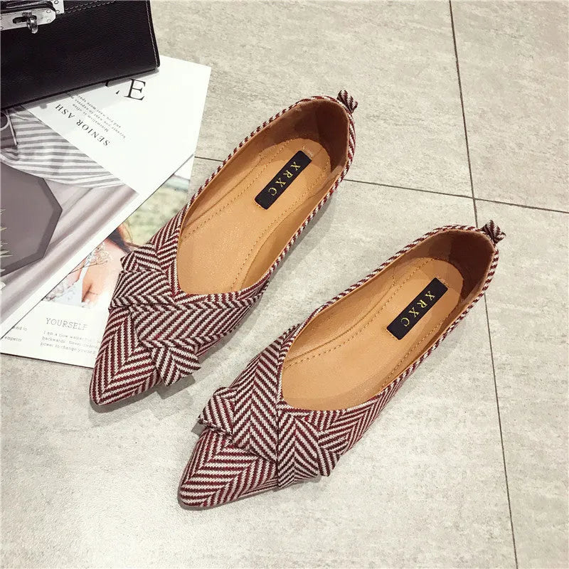 Women's red pointed toe shallow mouth flats with a low flat heel on a white background.