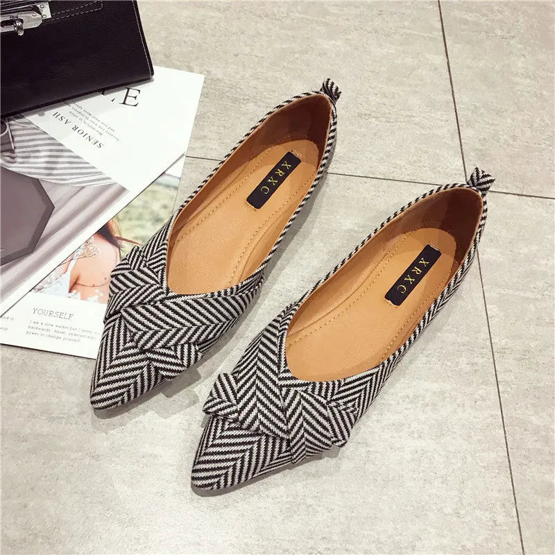 Women's red pointed toe shallow mouth flats with a low flat heel on a white background.