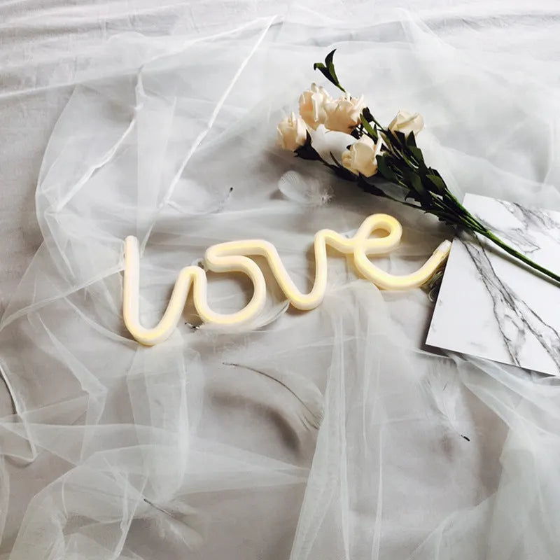 Pink love-shaped LED neon sign light with flexible silicone shell on a table.
