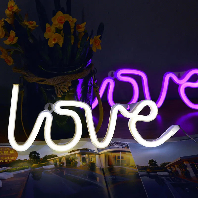 Pink love-shaped LED neon sign light with flexible silicone shell on a table.
